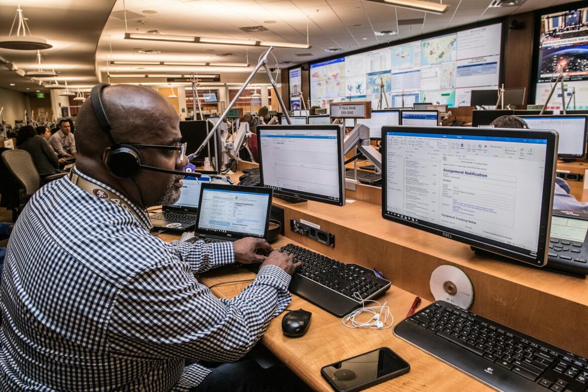 Focused man in office working on computers, engaged in technical research and communication.